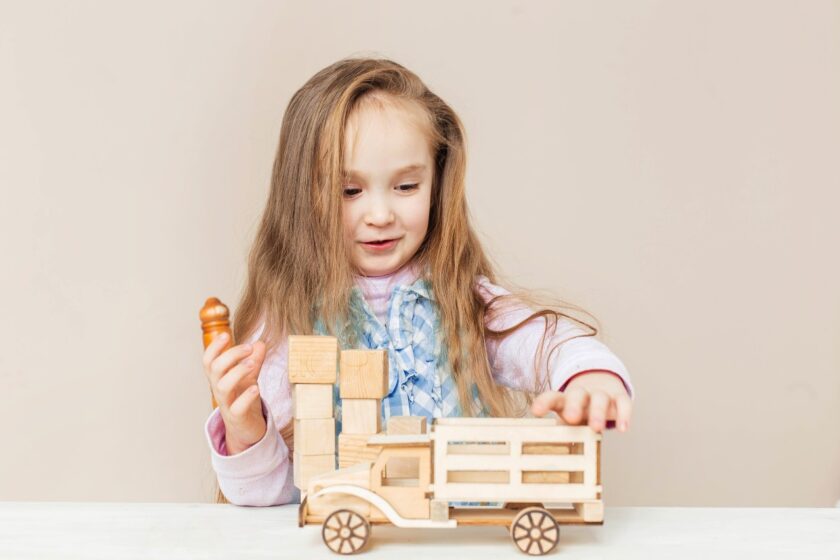 Little girl playing with a wood truck.