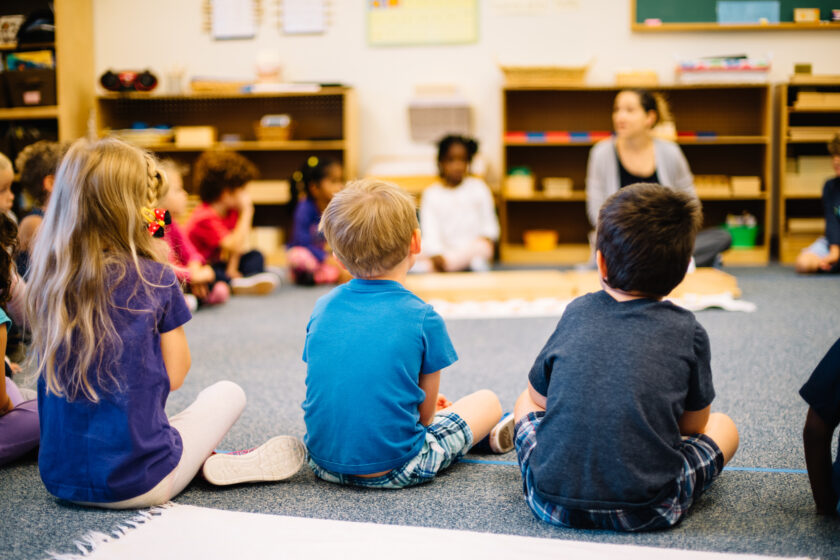 Kids sitting in a circle and listening to an instructor.