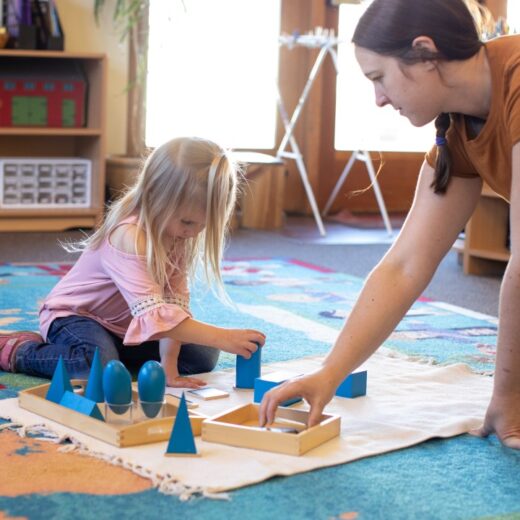 Little girl using Montessori blocks and instructor watching.